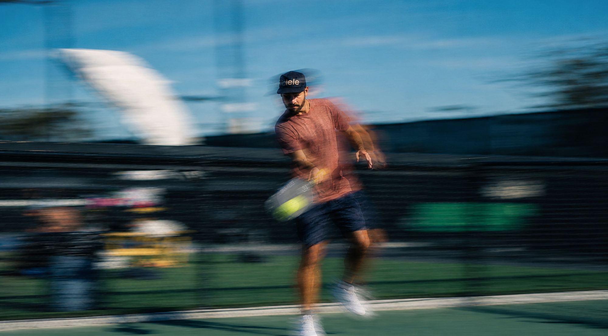 A player mid-stride on a pickleball court, caught in motion